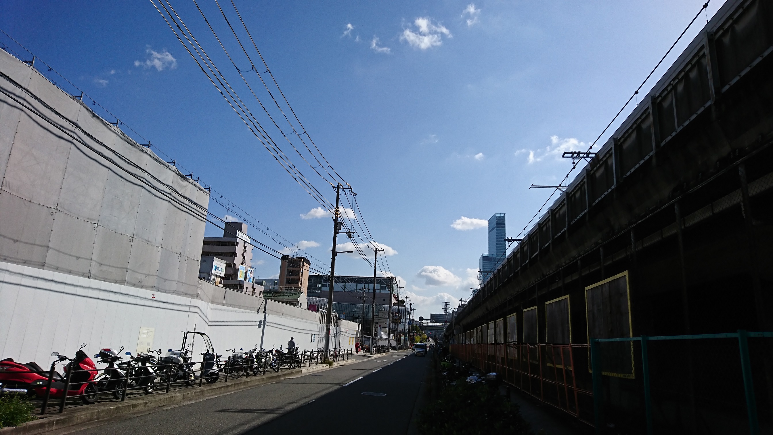 右手はJR新今宮駅の高架、左手はホテル建設現場。奥に「あべのハルカス」が見える