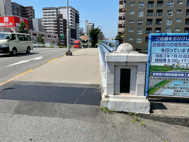 阪神なんば線「桜川駅」を利用する場合、建設地は道頓堀川にかかる汐見橋を渡るとすぐ。建設地の西側（写真左奥）には大型スーパーも備わっている