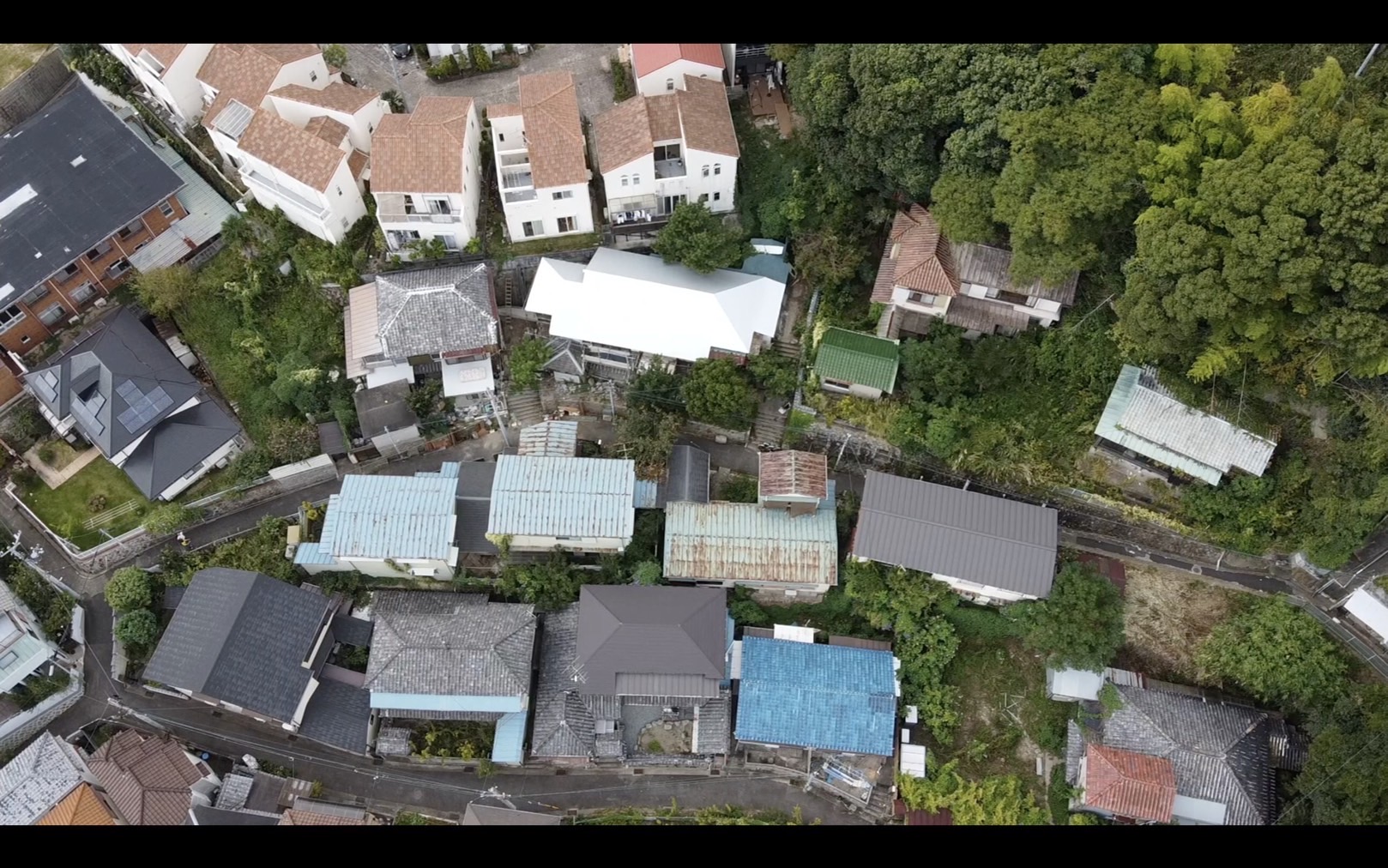 バイソンエリアを上空から見たところ。写真中央の路地を挟んで中央部、真っ白な屋根がバイソンギャラリーでその左右（右側はひとつの敷地内に小屋も含めて３軒、手前の薄い水色の３軒＋その隣のグレーの屋根がバイソン内 
